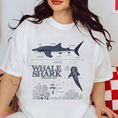 a woman wearing a white t - shirt with an image of a shark on it