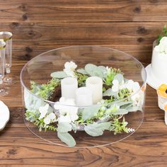 a table topped with a cake covered in frosting and greenery next to candles