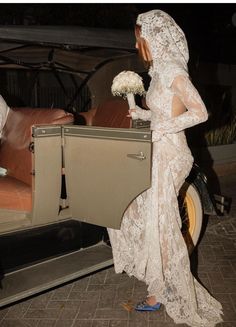 a woman in a wedding dress getting out of a car