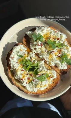 a white plate topped with two pieces of bread covered in feta cheese and herbs