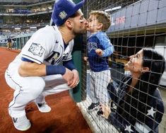 a man kissing a little boy in the dugout at a baseball game with his mom and dad