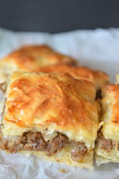 some meat and cheese pastries are sitting on wax paper with the words ground beef squash phyllo pie