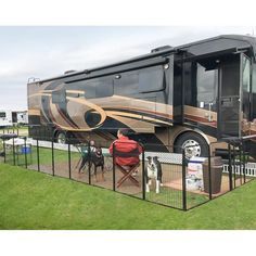 a large motor home sitting on top of a lush green field next to a dog