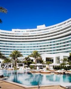 the hotel and pool are surrounded by palm trees