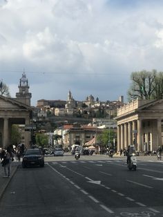 a city street filled with lots of traffic next to tall buildings on top of a hill