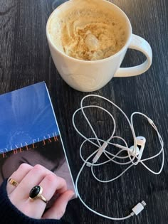 a cup of coffee sitting on top of a wooden table next to a pair of headphones