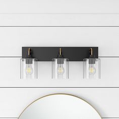 three lights on the wall above a mirror