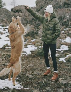 a woman is playing with her dog in the snow