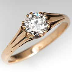 an old - fashioned diamond ring is displayed on a white surface, with gold accents