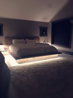 a large bed sitting in the middle of a bedroom next to two night stands with lights on them