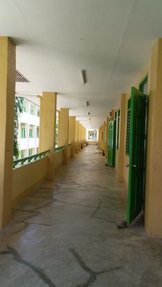 a long hallway with yellow walls and green doors leading to the rooms on each side