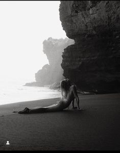 a woman laying on the beach next to some rocks