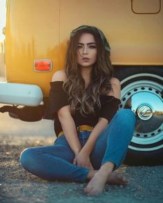 a woman sitting on the ground next to a yellow van