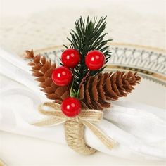 pine cones and berries are tied to twine on a napkin with white linens