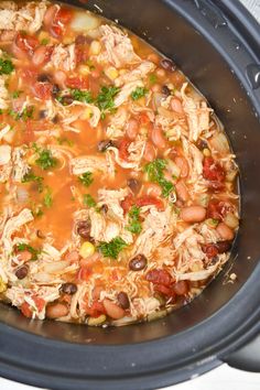 a crock pot filled with beans, meat and vegetables