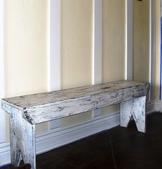 a white bench sitting in front of a wall