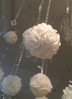 some white flowers hanging from a ceiling with crystal beads and chains attached to the ceiling