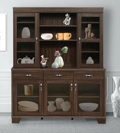 a brown wooden cabinet with glass doors and plates on it's shelves in a living room