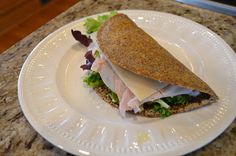 a white plate topped with a cut in half sandwich on top of a marble counter