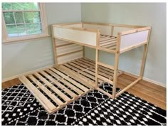 a wooden bunk bed sitting on top of a black and white rug next to a window