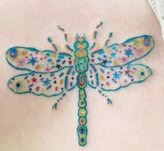 a colorful dragonfly tattoo on the back of a woman