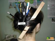 the back of a woman's head with rulers and pencils in her hair