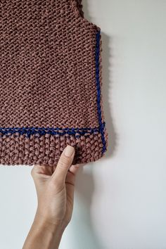 a hand is holding up a crocheted piece of cloth that looks like a blanket