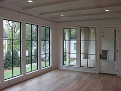 an empty room with large windows and wood floors