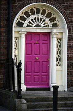 a bright pink door sits in front of an arched doorway