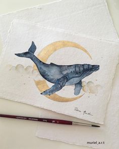 a watercolor painting of a humpback whale on white paper next to a pencil