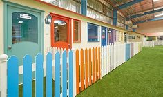 an indoor play area with fake grass and colorful doors on the side of the building