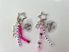 two key chains with charms attached to them on top of a white table next to each other