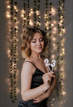 a woman in a black dress holding a cake topper with the number twenty five on it