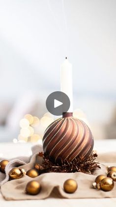 a white candle is sitting on top of a brown and gold ball ornament