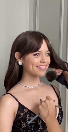 a woman is getting her hair done in front of an open door and smiling at the camera