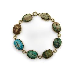 This is part of Chairish’s Fine Jewelry assortment.  This 18k gold bracelet contains eight scarabs in various shades of blues, greens, and browns, each with a unique hieroglyphic. Made from clay, the scarab beads get their coloring when copper within the clay turns turquoise during the firing process; no two scarabs are alike and their rustic nature make this piece fascinating to look at. The 18k gold bezel mounts have a saw tooth that adds a graphic and holds the scarabs in place. The hand-carv Scarab Bracelet, Ancient Languages, 18k Gold Bracelet, Scarab Beetle, Archaeological Finds, Egyptian Revival, Shades Of Blue, Gold Bracelet, 18k Gold