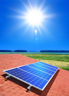 a solar panel on the roof of a house with blue sky and green grass in the background