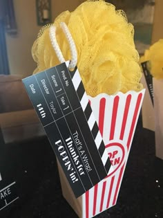 a popcorn box with yellow flowers in it on a black countertop next to a white bag