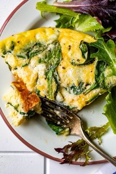 an omelet with spinach and cheese on a plate next to a salad