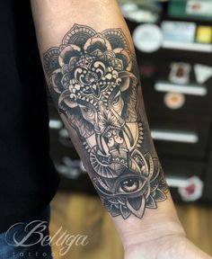 an elephant tattoo on the arm with flowers and paisleys around it's neck