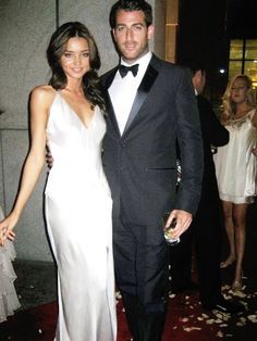 a man in a tuxedo standing next to a woman in a white dress