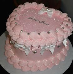 a pink cake with white bows and pearls