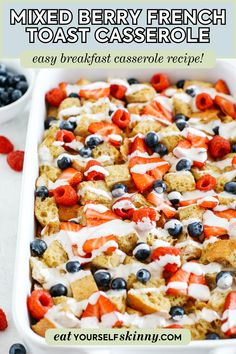 mixed berry french toast casserole in a white baking dish with berries and yogurt