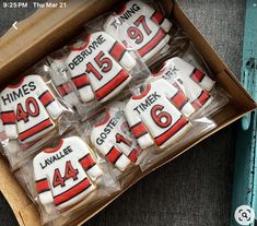 decorated cookies in the shape of hockey jerseys are sitting in a cardboard box on a table