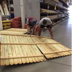 two men working on wood planks in a warehouse