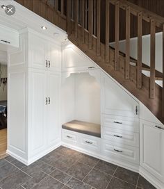 an open closet under the stairs in a house with white cabinets and drawers on either side