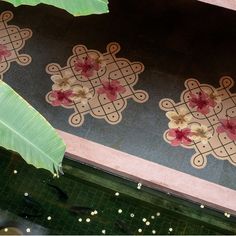 the floor is decorated with flower designs and green leaves in front of a mirror reflecting water