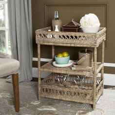 a wicker serving cart with two lemons and a bowl on it in front of a window