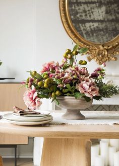 a vase filled with flowers sitting on top of a wooden table next to a mirror