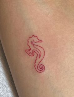 a small red seahorse tattoo on the back of a woman's leg,